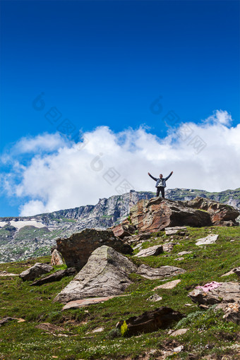 山坡<strong>石块</strong>上站着的旅行者摄影图