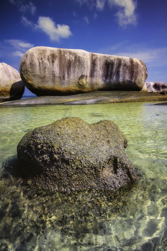 蓝天下浸泡在<strong>海</strong>水<strong>中</strong>的礁石摄影图