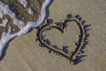 海边沙滩上情侣画心心摄影图