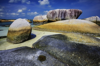 蓝天白云下海滩细砾岩石摄影图