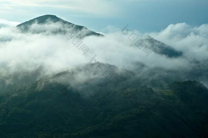 户外风光天空中白云中的山峰摄影图