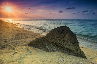 海边日出海滩上的石头摄影图