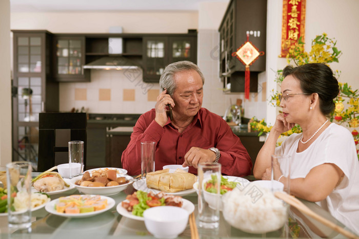 暖色调聚餐中打电话的老人摄影图