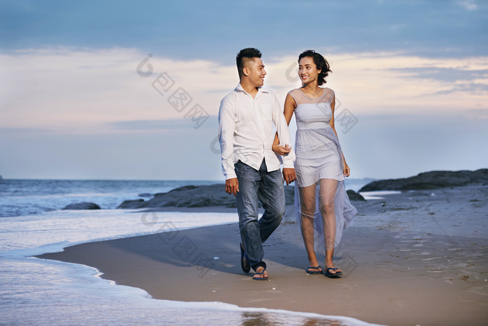 蓝色调海边散步的情侣摄影图
