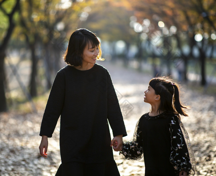 妈妈牵着女儿的手在公园散步