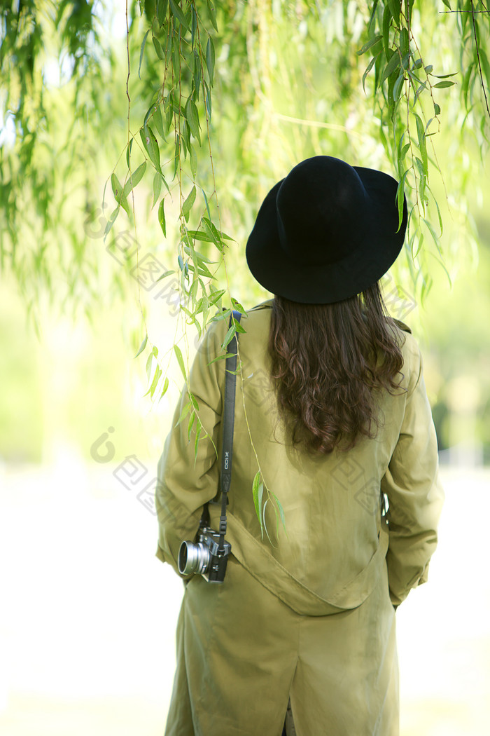 戴着帽子在柳树下看风景的美女背影