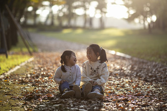 可爱<strong>姐妹</strong>坐在落叶地上开心玩耍