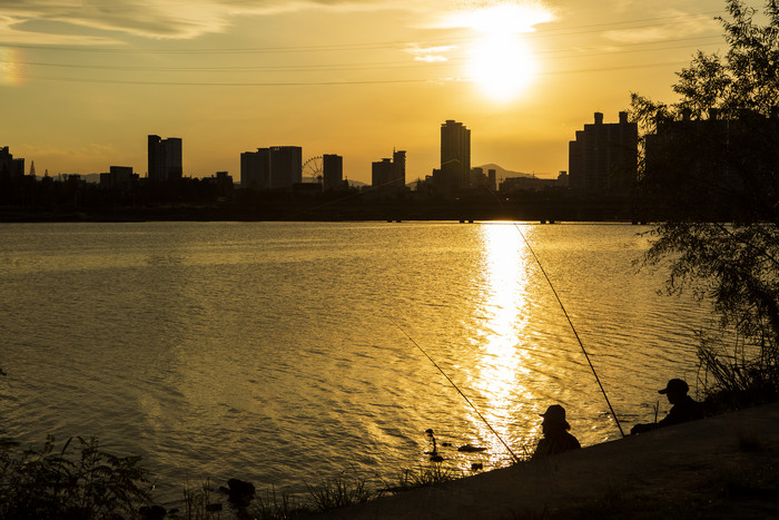 金色夕阳和坐在湖边垂钓的人