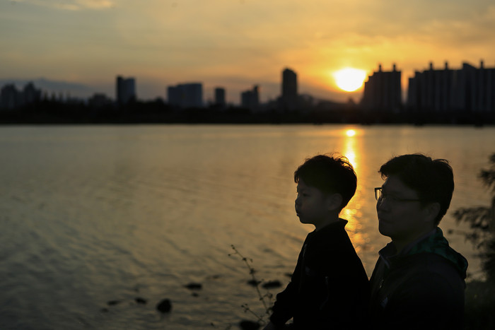 夕阳下坐在湖边的两父子