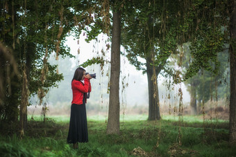 森林中拿着相机在拍照的女人