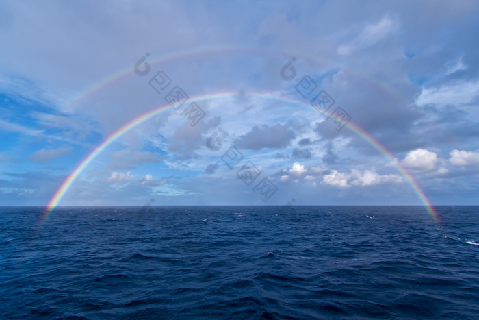 蓝色天空下出现在海上的两轮彩虹