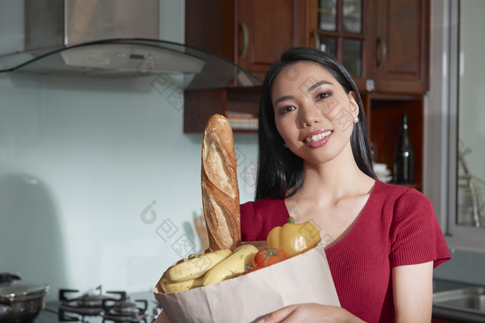 年轻妈妈在厨房抱着食物