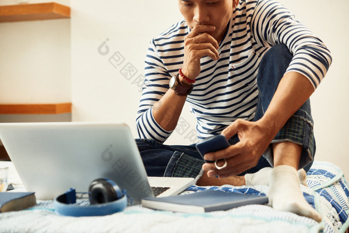 男人坐在床上看电脑手机