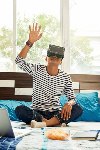 坐在床上使用虚拟VR眼镜