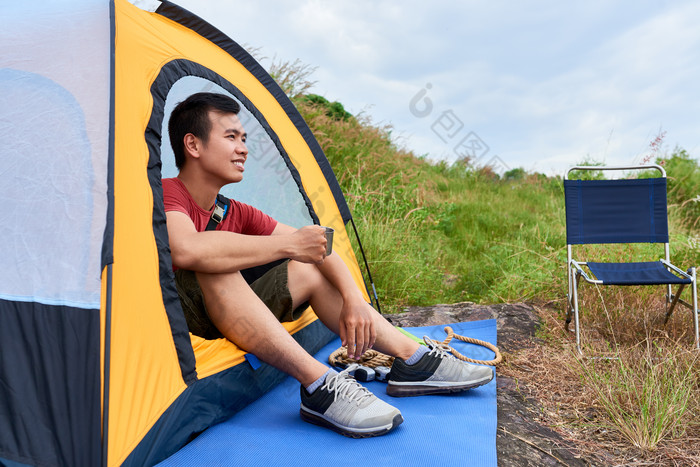 在帐篷边喝茶的男人