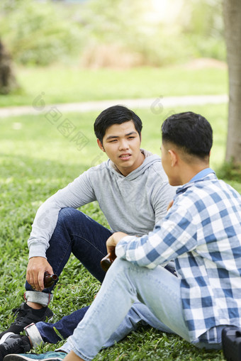 坐在草地上交流的男生
