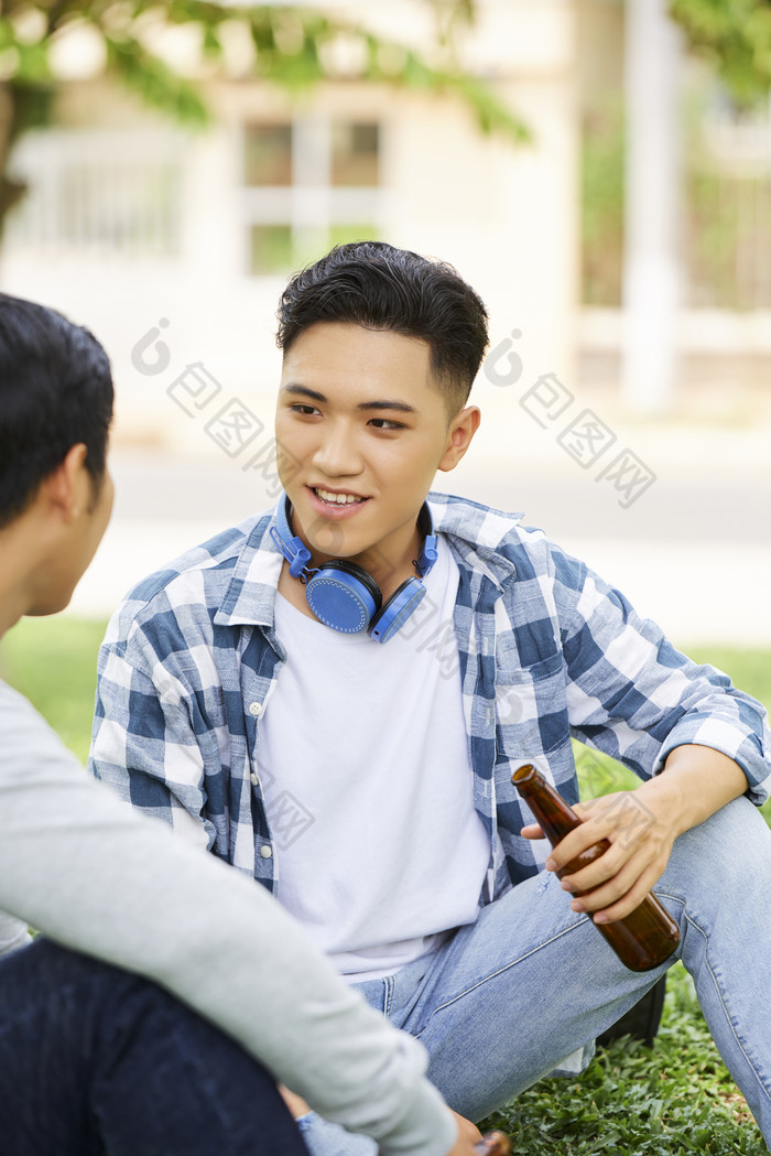 坐在草地上喝酒交流的年轻人