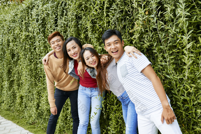 在篱笆前面拍照的年轻人图片-包图网