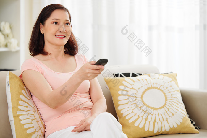 女人坐在沙发上使用遥控器