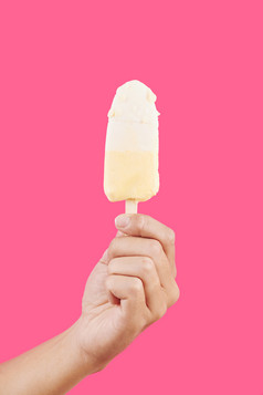 粉色背景前拿着奶油冰激淋雪糕
