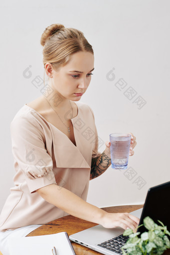 举着水杯在电脑上发信息的女人