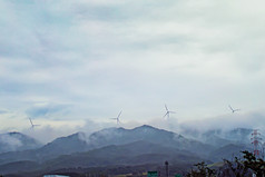 雨后朦胧雾气山体风力发电机摄影图