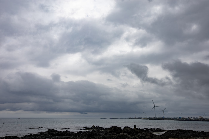 阴暗海上天气风力发电机摄影图