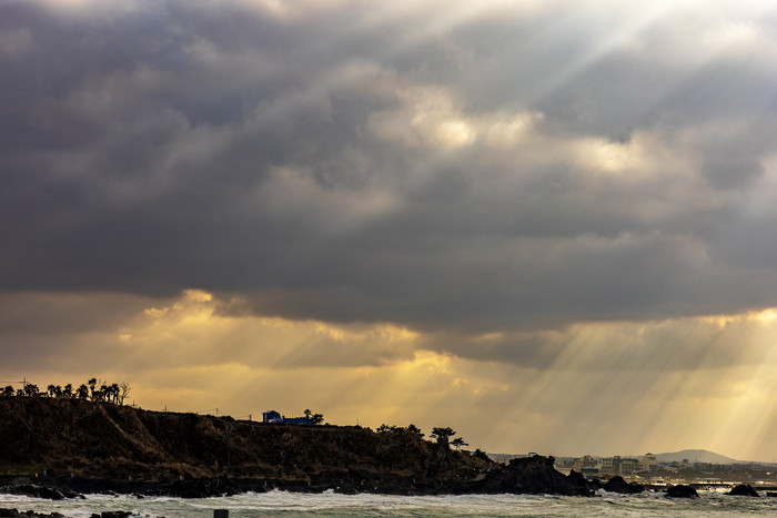 日光穿越云层海岸边摄影图
