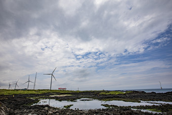 美丽海岸边风力发电机摄影图