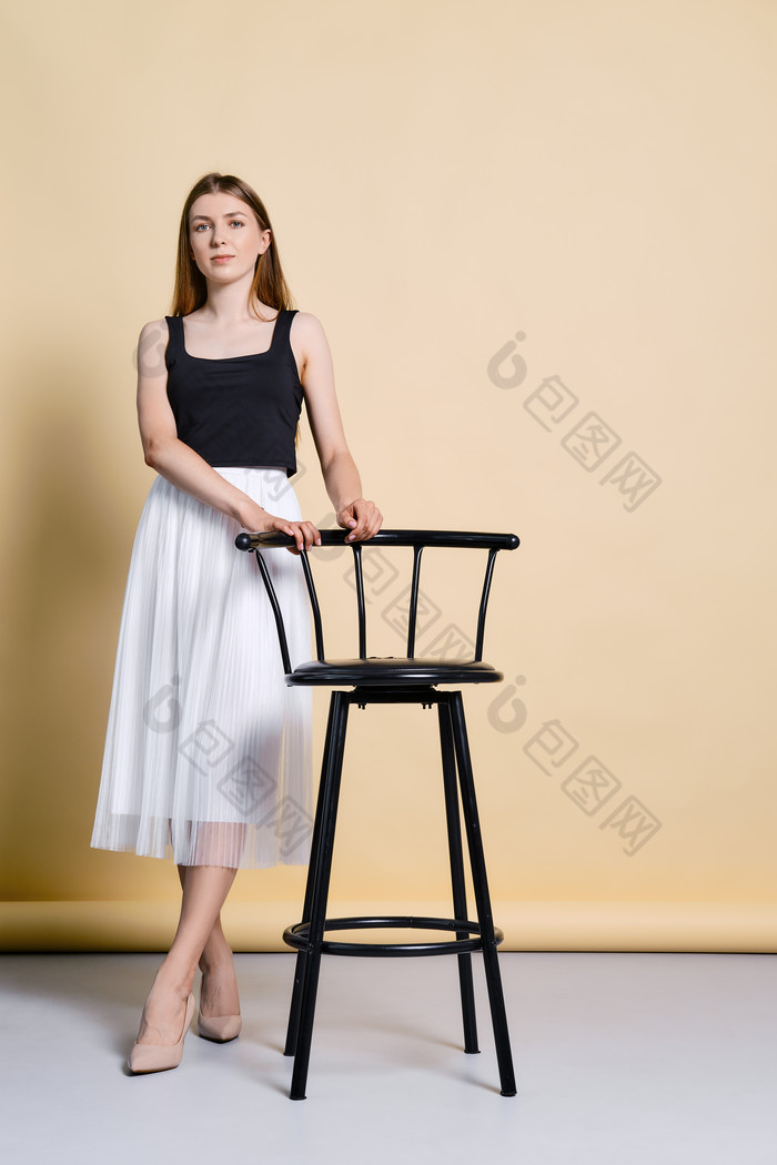 女孩扶着黑色椅子摄影图