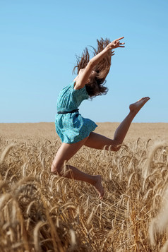 女孩在草地上跳跃摄影图