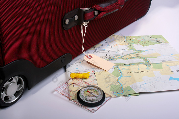 行李箱旁边的地图和指南针
