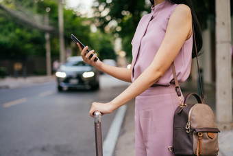 女人推着行李箱街道等车