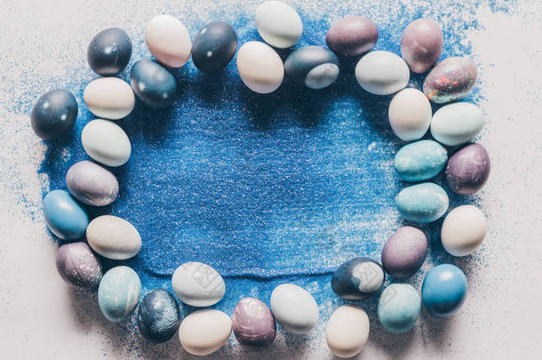 白色表面涂上复活节<strong>彩蛋</strong>和蓝色沙子的最高视图