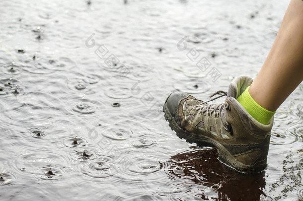 人在<strong>徒步</strong>旅行靴走在雨中的水