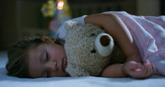 宝宝休息静静地躺在床上抱着泰迪熊玩具，和平的梦想和无噪声、 快乐的孩子们和妈妈和爸爸幸福家园的概念。在睡梦中，无咳嗽儿童幸福.