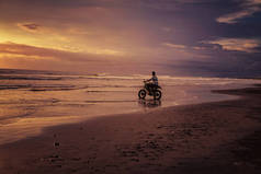 日出时骑摩托车进入大海的人