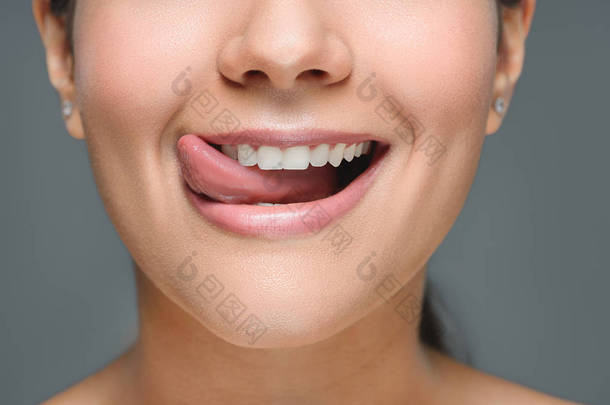 白色牙齿贴舌的微笑妇女的部分看法灰色隔离