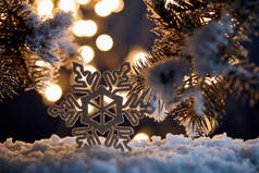 在雪地里，用云杉枝条和模糊的圣诞彩灯把装饰过的雪花包在一起 