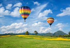 热气球在黄花场与山和蓝色天空背景