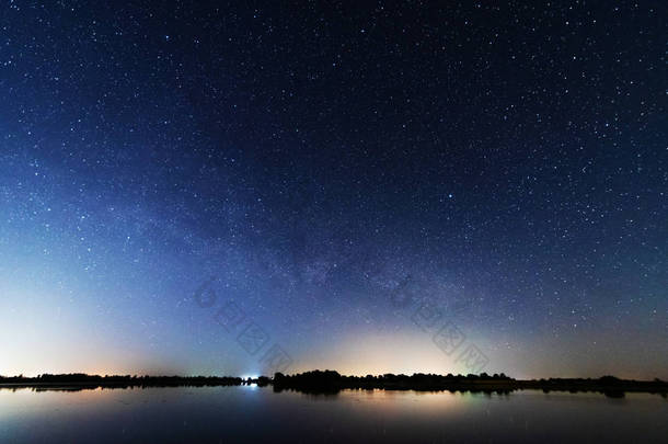 在河岸上的一个迷人的<strong>星夜</strong>，有一棵大树，天空中的一条银河，夏天有流星坠落.