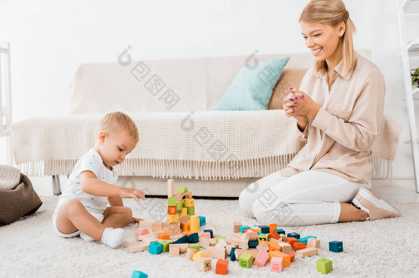 可爱的<strong>幼儿</strong>玩五颜六色的立方体和母亲在托儿所室