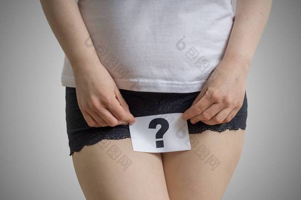阴道或尿路感染和问题的概念。年轻女人抱着纸用问号以上裆.