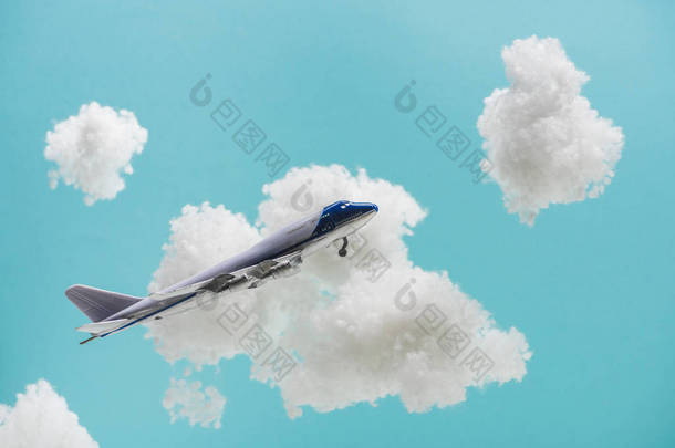 玩具飞机在白色蓬松的云彩中飞行，这些云彩是用蓝色孤立的棉毛制成的