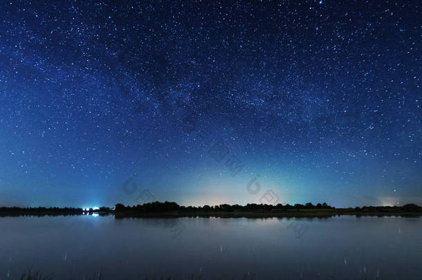 在河岸上的一个迷人的星夜，有一棵大树，天空中的一条银河，夏天有流星<strong>坠落</strong>.