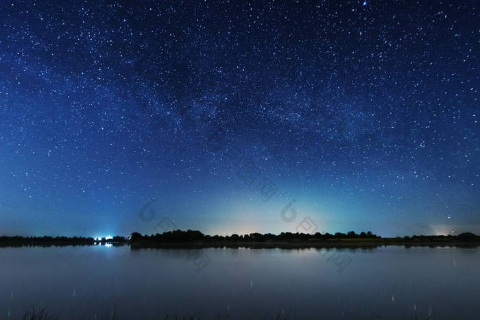 在河岸上的一个迷人的星夜，有一棵大树，天空中的一条银河，夏天有流星坠落.