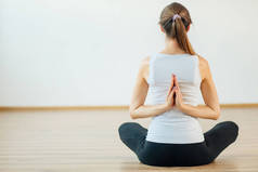 妇女练习瑜伽与合十背后的背部