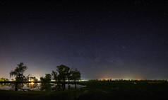 夜空中有银河系的星星的空间。与河和树的风景被拍照在长的曝光.