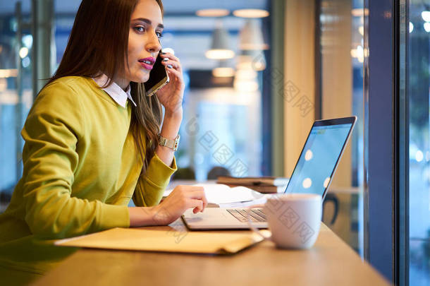 年轻女子下载现代<strong>应用</strong>程序坐在咖啡馆室内与笔记本电脑使用 wifi 连接