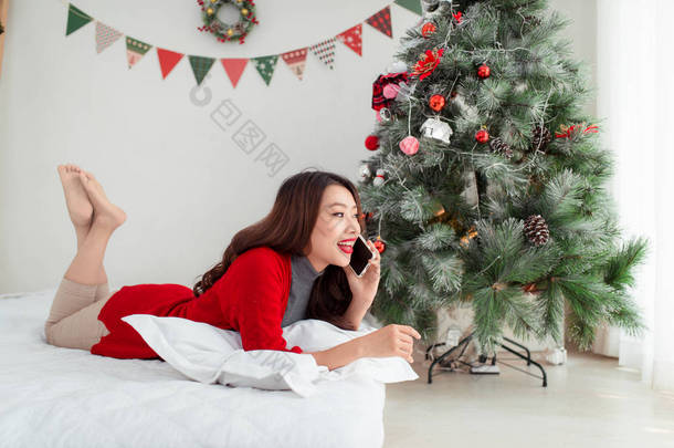 亚洲女人躺在圣诞节树附近